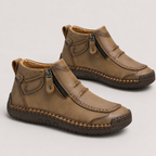 A pair of toddler ankle boots in brown faux leather, featuring a side zipper, decorative stitching, and a dark brown sole, shown on a light gray background.
