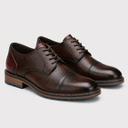 A pair of dark brown textured leather cap-toe oxford shoes with matching laces, displayed on a clean light gray background.