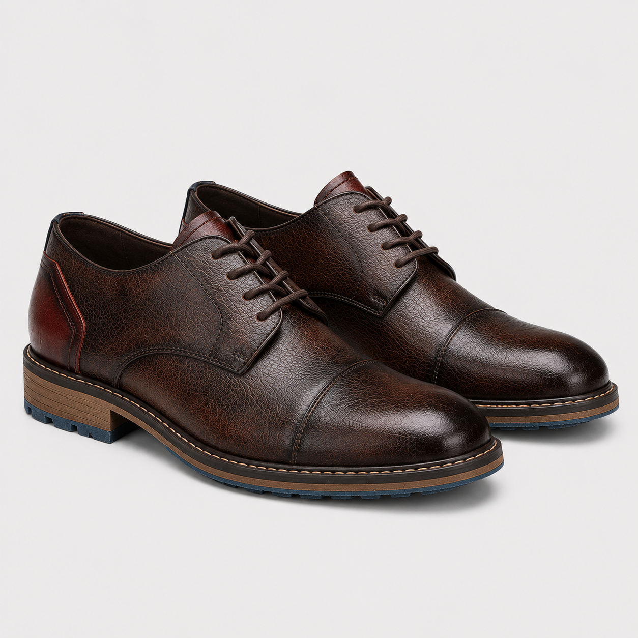A pair of dark brown textured leather cap-toe oxford shoes with matching laces, displayed on a clean light gray background.