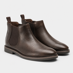 A pair of dark brown leather Chelsea boots with elastic side panels and pull tabs, shown on a light gray background.