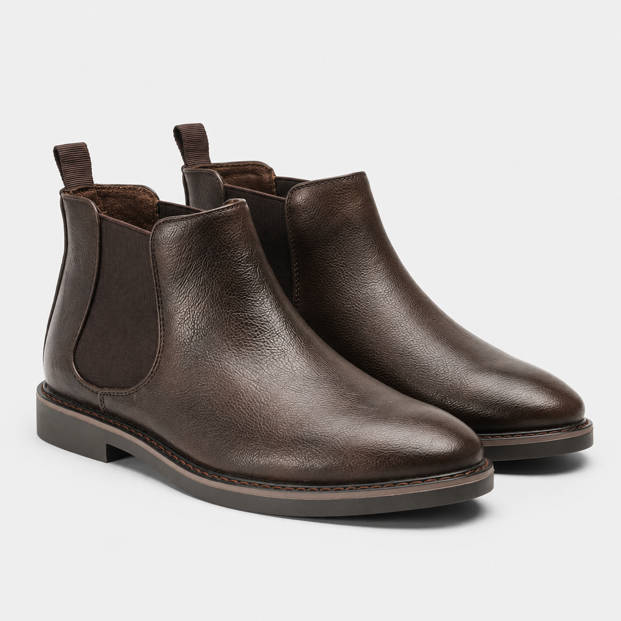 A pair of dark brown leather Chelsea boots with elastic side panels and pull tabs, shown on a light gray background.