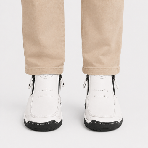 White ankle boots with black soles and side zippers, shown on a model wearing beige trousers against a light gray background.