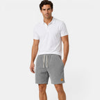 Man wearing a white polo shirt and gray shorts on a white background