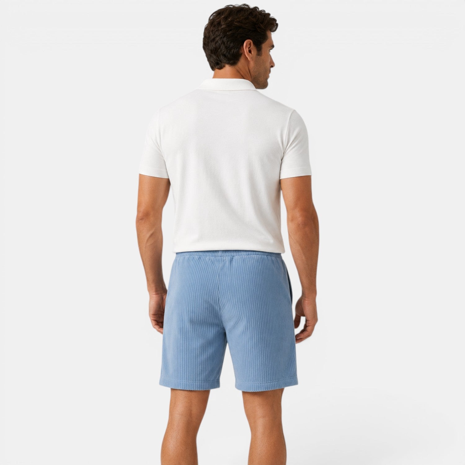 Man wearing a white polo shirt and light blue shorts on a white background