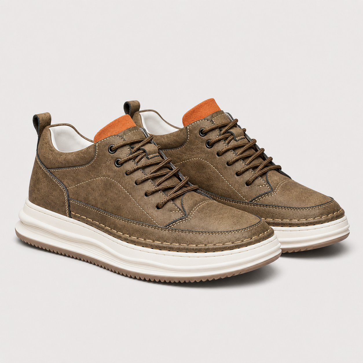 A pair of mid-top lace-up sneakers in brown suede and canvas, featuring a thick white platform sole and orange accents on the collar lining.