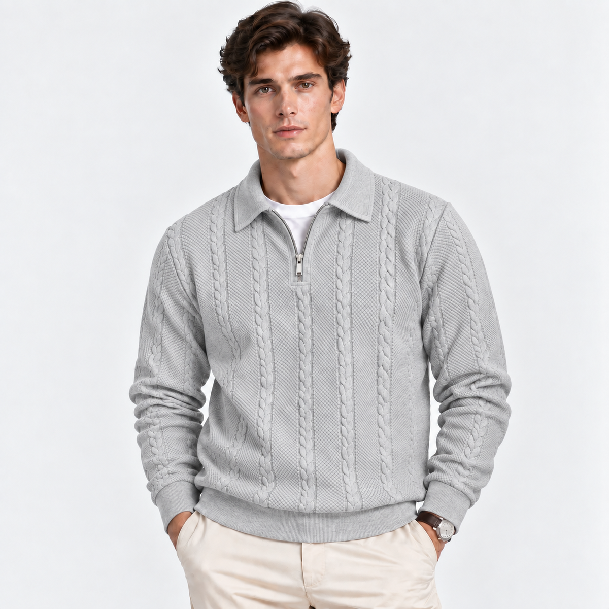 A man wearing a light gray cable-knit quarter-zip sweater over a white t-shirt and beige pants, standing against a plain white studio background.