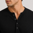 Close-up of a man wearing a black Henley shirt with a three-button placket, showing the fabric texture and neckline details.