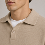 Close-up of a man wearing a beige knit polo shirt over a white crew-neck t-shirt, showing the collar, button, and textured fabric.