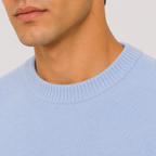 Close-up of a man wearing a light blue crew-neck knit sweater, showing the ribbed collar and fine knit texture against a plain light background.