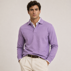 A man wearing a light purple long-sleeve polo sweater over a white collared shirt, paired with beige trousers and a dark brown belt, standing against a plain light beige studio background.