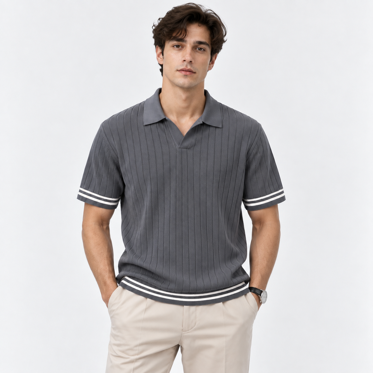 A man wearing a dark gray ribbed short-sleeve polo shirt with white stripe accents on the collar, cuffs, and hem, paired with beige trousers, against a plain light gray background.