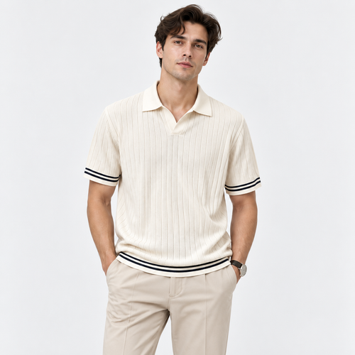 A man wearing a cream-colored ribbed short-sleeve polo shirt with black and white striped trim on the collar, cuffs, and hem, paired with beige trousers, against a light gray studio background.