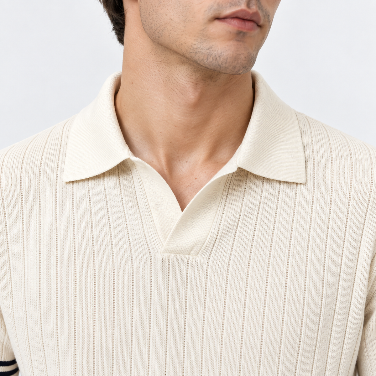 Close-up of a man wearing a cream ribbed knit polo shirt with a collar and split V-neck.