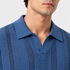 Close-up of a man wearing a textured blue knit polo shirt with a collar and openwork knit pattern, against a light gray background.