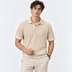 A man wearing a beige ribbed short-sleeve polo shirt with white stripe accents on the collar, cuffs, and hem, paired with beige trousers, against a plain white studio background.