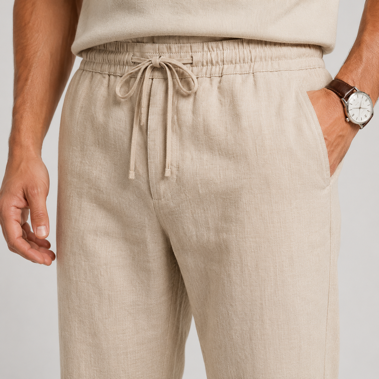 Beige linen drawstring trousers shown on a model, featuring an elastic waistband, side pockets, and a relaxed fit.