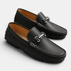 Pair of black leather loafers with a silver buckle on a white background