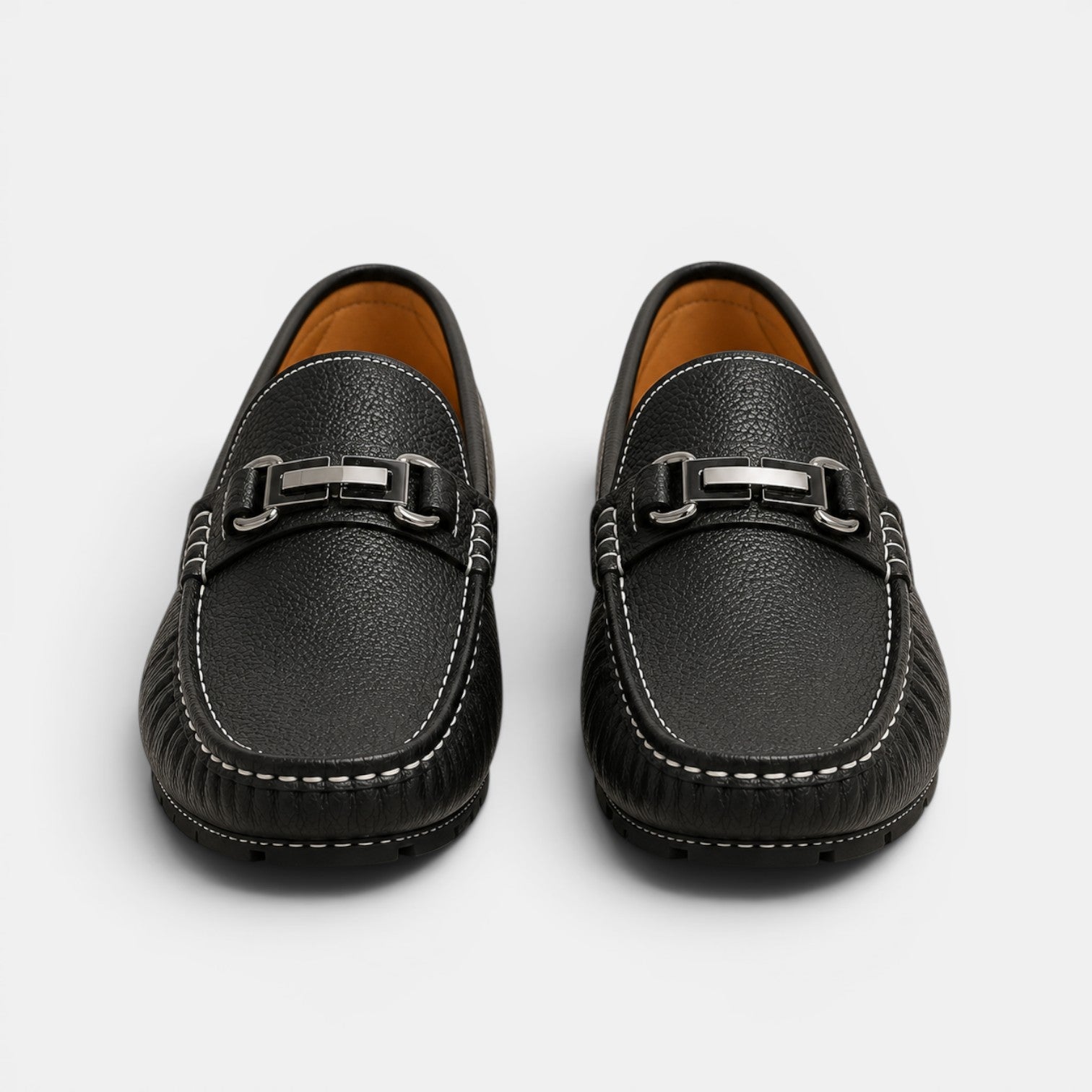 Pair of black leather loafers with silver buckles on a white background