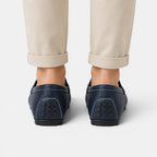 Navy loafers worn with beige pants on a white background