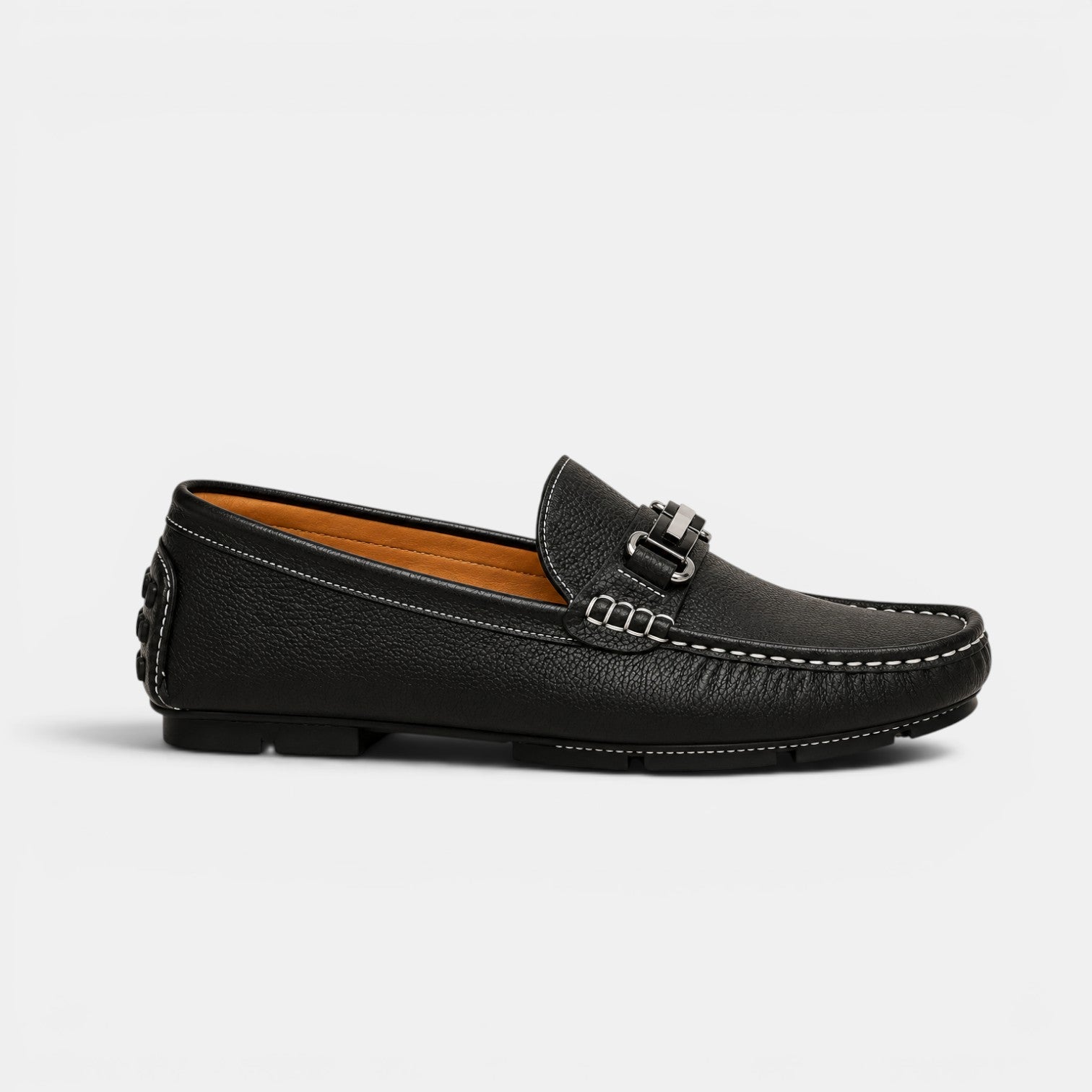 Black leather loafer with a decorative buckle on a light gray background