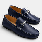 Pair of navy blue loafers with silver buckles on a light gray background