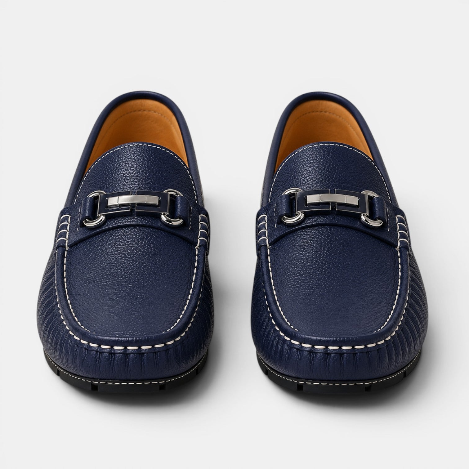 Pair of navy blue loafers with silver buckles on a light gray background