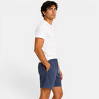 Man wearing a white t-shirt and blue shorts on a plain background