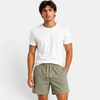Man wearing a white t-shirt and green shorts on a plain background