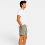 Man wearing a white t-shirt and green shorts on a plain background
