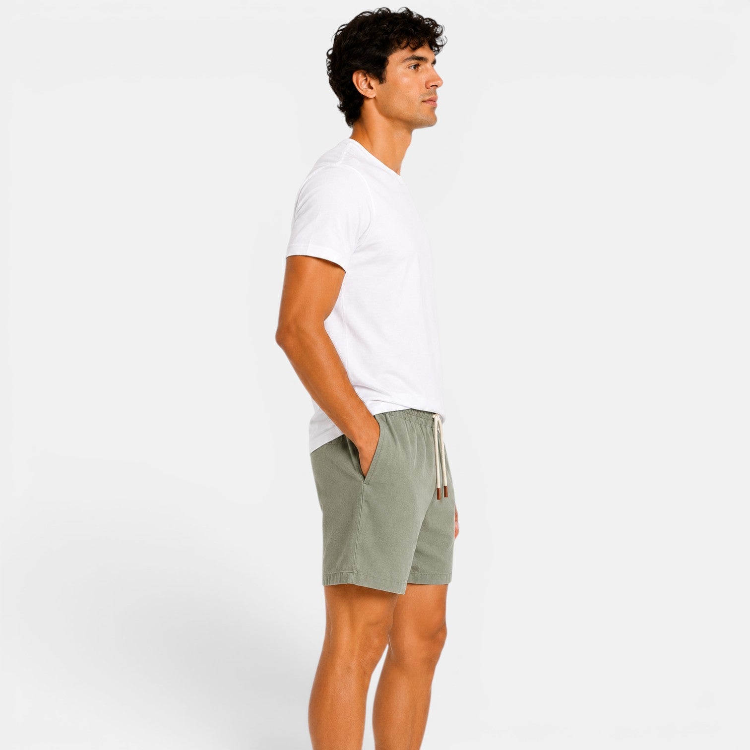 Man wearing a white t-shirt and green shorts on a plain background