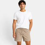 Man wearing a white t-shirt and beige shorts on a plain background