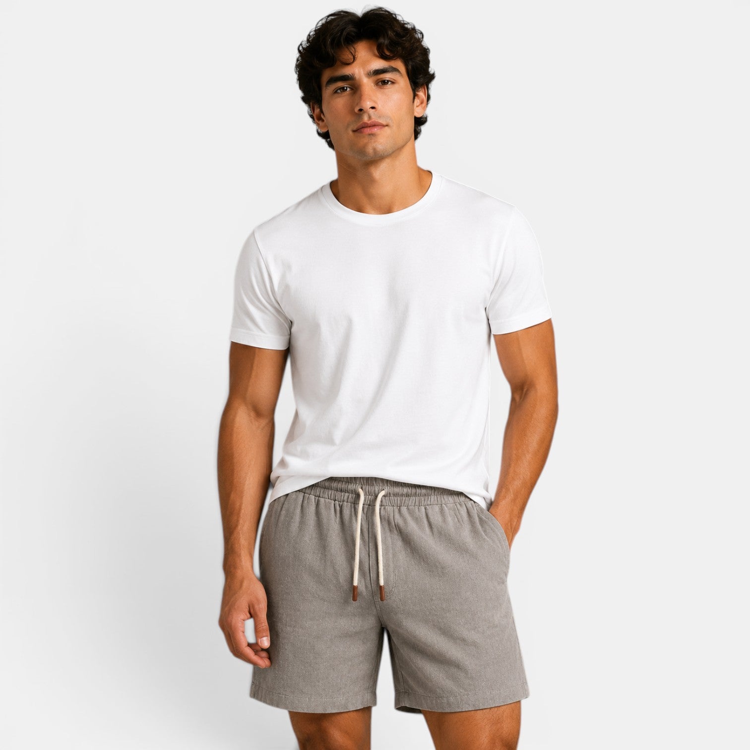 Man wearing a white t-shirt and gray shorts on a plain background