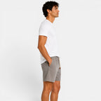 Man wearing a white t-shirt and gray shorts on a plain background