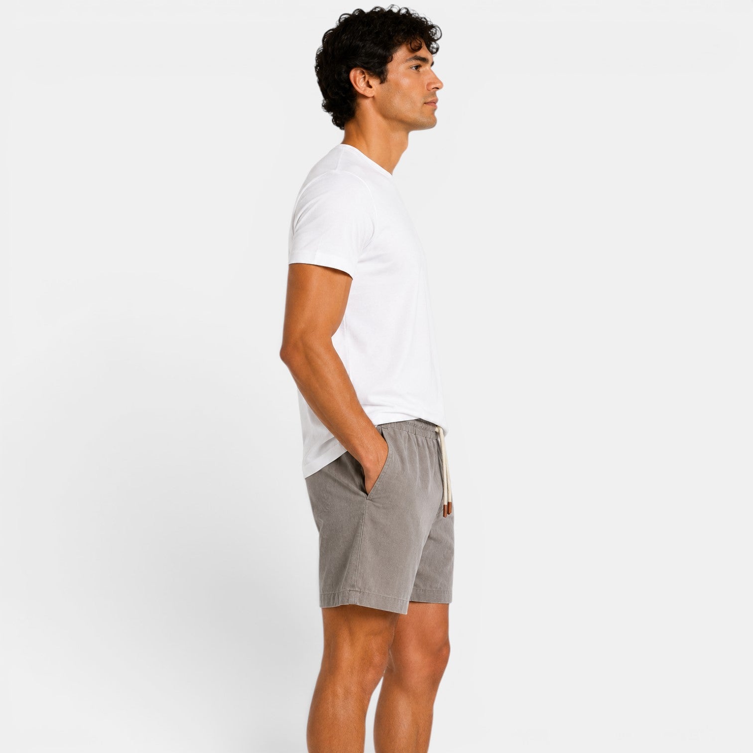 Man wearing a white t-shirt and gray shorts on a plain background
