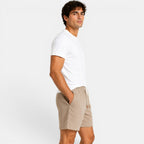 Man wearing a white t-shirt and beige shorts on a plain background