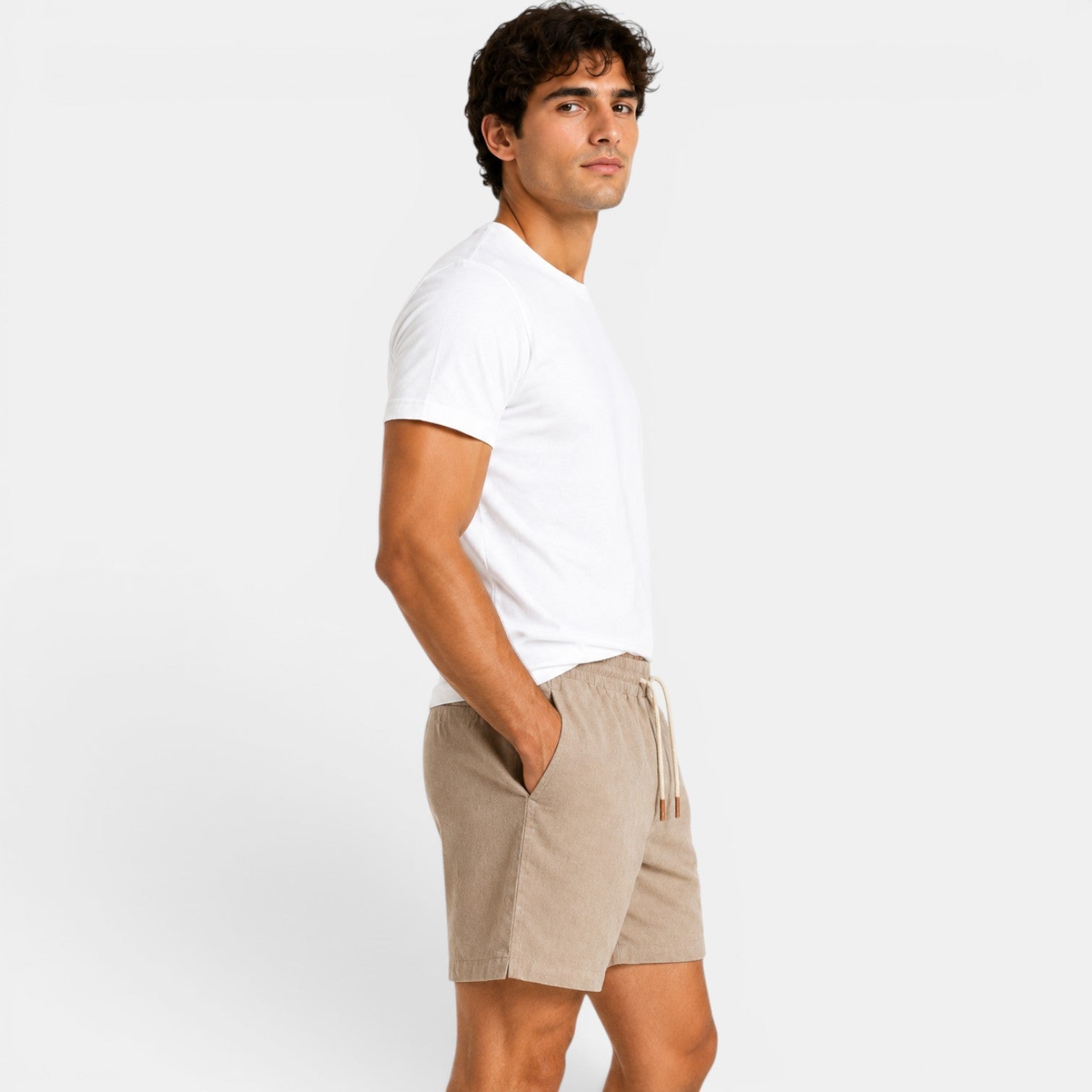 Man wearing a white t-shirt and beige shorts on a plain background