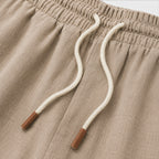 Close-up of beige shorts with white drawstrings and brown ends.