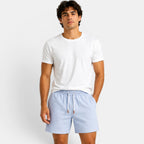 Man wearing a white t-shirt and light blue shorts on a plain background