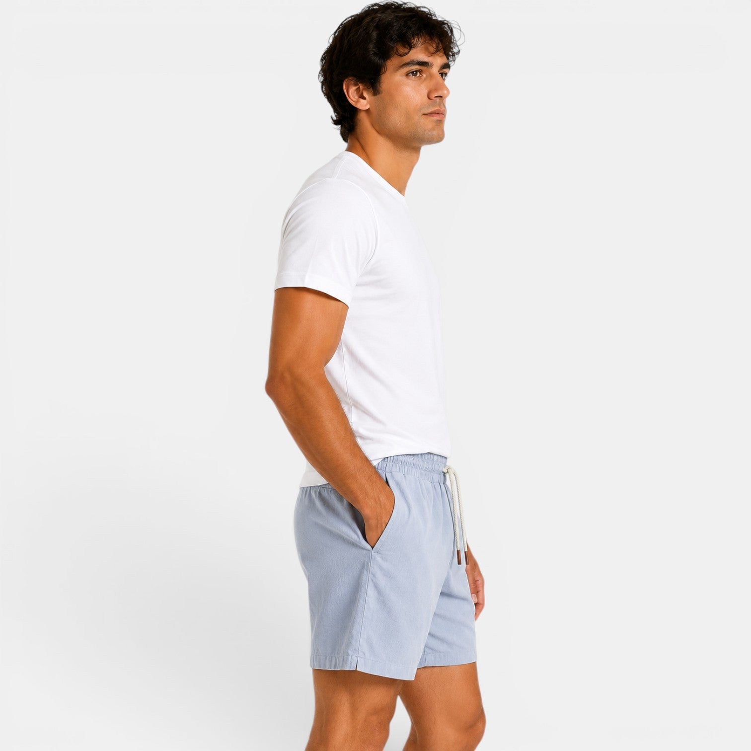 Man wearing a white t-shirt and light blue shorts on a plain background