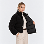 Side view of a woman wearing a black quilted puffer jacket with high collar and snap buttons