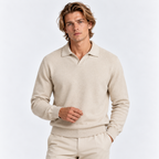 A man wearing a light beige knit polo sweater and matching beige trousers, photographed against a clean white studio background.