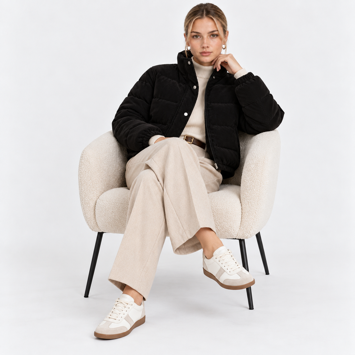 Woman wearing a black quilted puffer jacket with cream trousers while seated