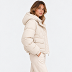 Side view of a woman wearing a cream quilted hooded puffer jacket
