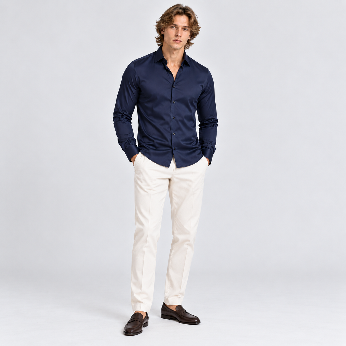 Man wearing a navy blue button-down shirt with white trousers and dark loafers