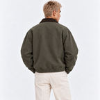 Back view of a man wearing an olive green jacket with brown collar