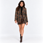 Woman wearing a brown plaid blazer with black top, leather skirt, and knee-high boots