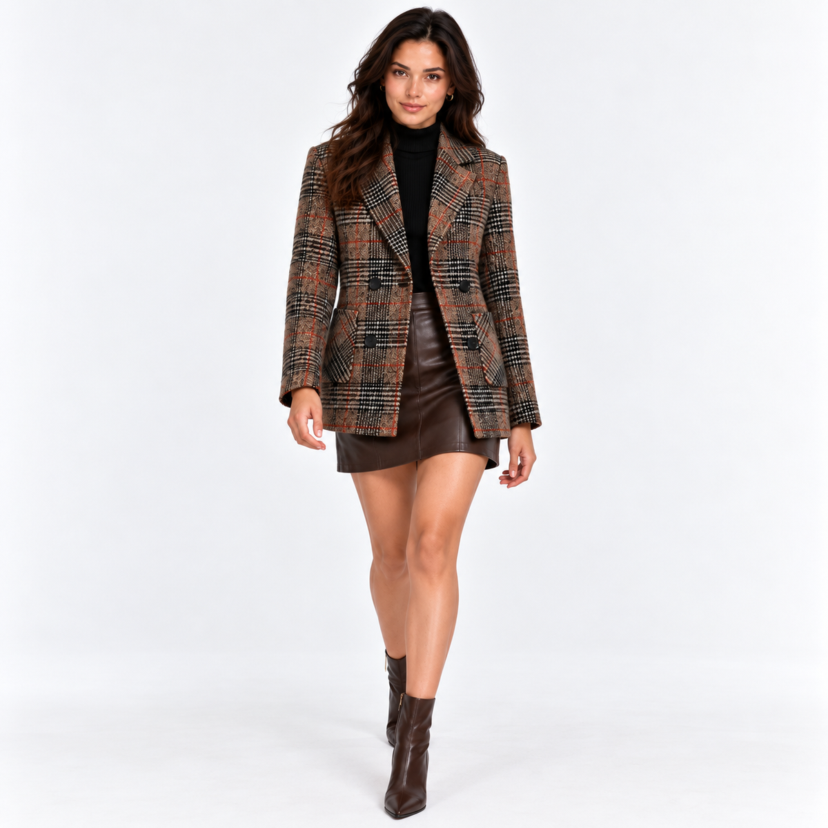 Woman wearing a brown plaid blazer with black top, leather skirt, and knee-high boots