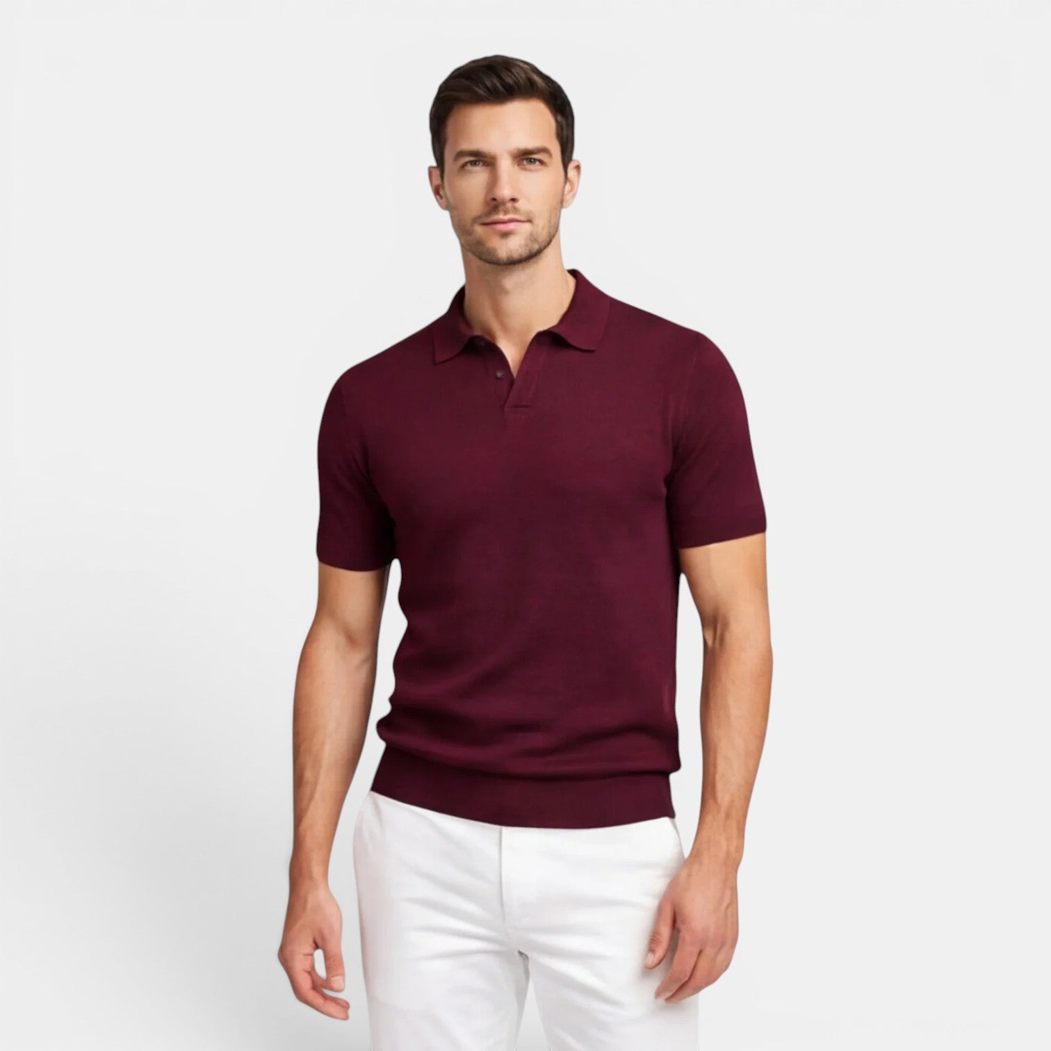 Man wearing a maroon polo shirt and white pants on a light gray background
