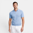 Man wearing a light blue polo shirt and white pants on a plain background