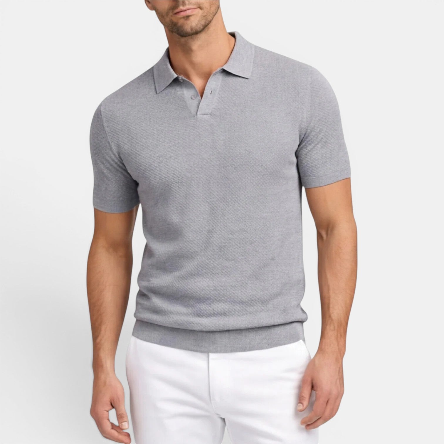 Man wearing a gray patterned polo shirt and white pants on a light gray background
